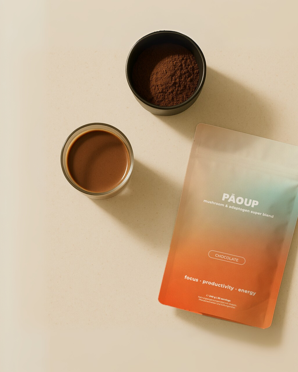 PAOUP Cacao with paoup cacao packaging with a cup of cacao functional mushrooms adaptogens and a container of paoup cacao powder on a beige background