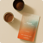 PAOPUP chocolate powder package with a cup of coffee and a bowl of ground coffee on a beige surface
